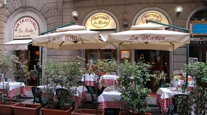 La facciata della Trattoria La Madia in Via del Giglio con i tavoli all’aperto sotto gli ombrelloni