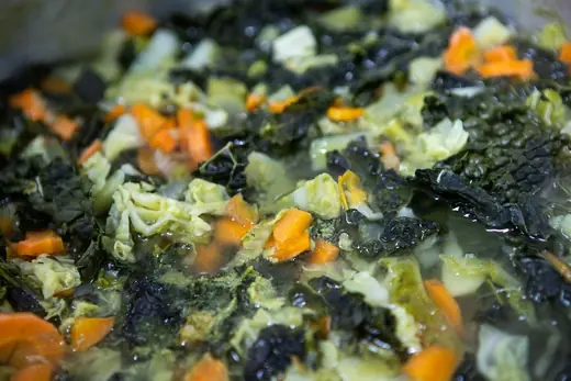 Cavolo nero, verza e carote che cuociono in pentola per la ribollita