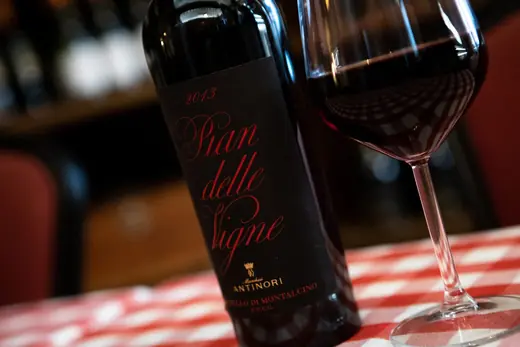 Bottiglia di Rosso di Montalcino e calice sul tavolo