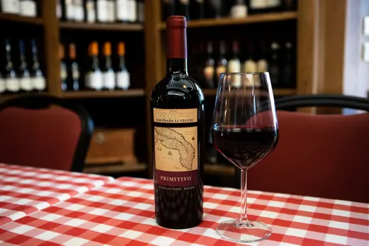 Bottiglia di vino e calice sulla tovaglia a quadretti