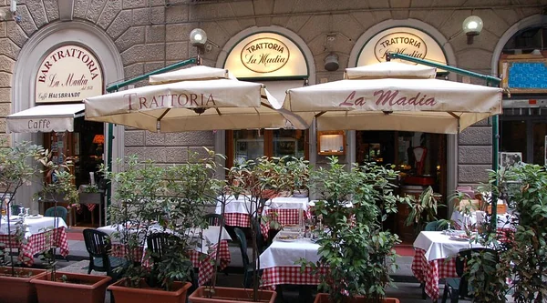 La facciata della Trattoria La Madia in Via del Giglio con i tavoli all’aperto sotto gli ombrelloni