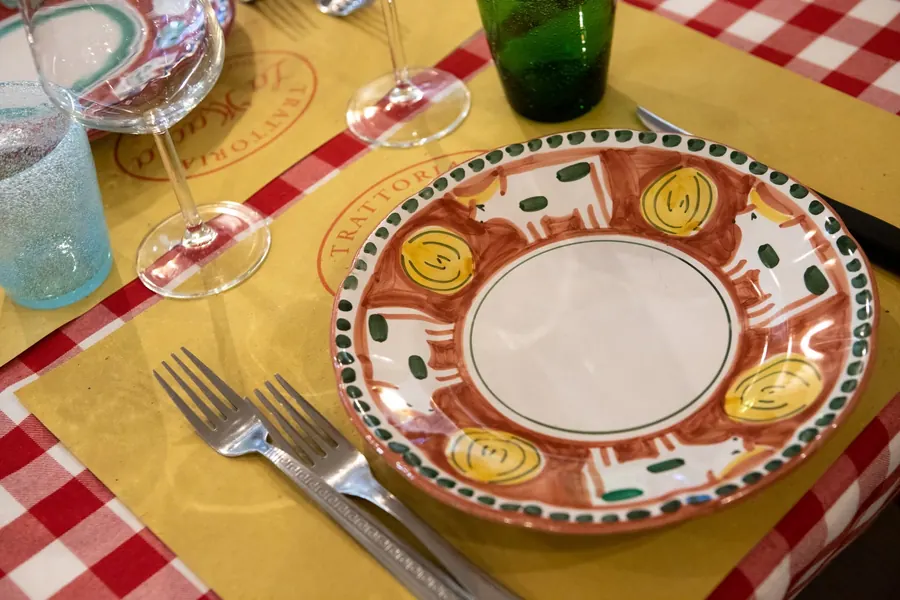 Tavolo apparecchiato con tovaglia a quadretti e piatto in ceramica dipinta